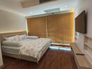 Modern bedroom with large bed, wooden blinds, and wall-mounted TV