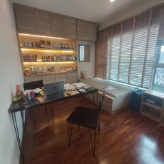 Home office with built-in shelves, wooden flooring, desk, and large window