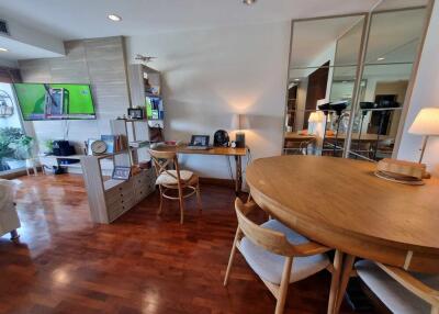 Living room with wooden flooring, dining table, and TV