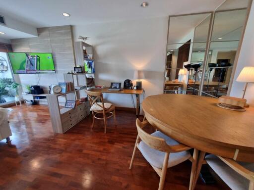 Living room with wooden flooring, dining table, and TV