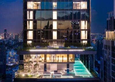 Modern high-rise building with illuminated windows and rooftop pool