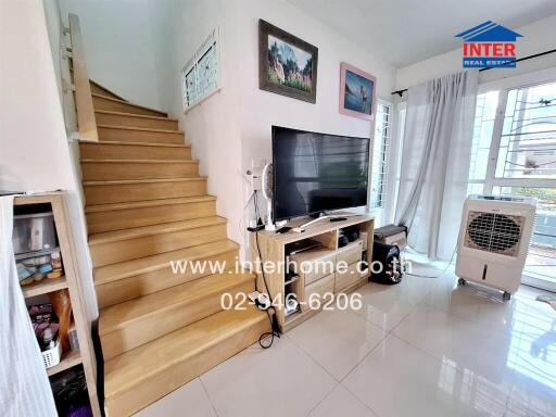 Living area with staircase, TV, and large windows