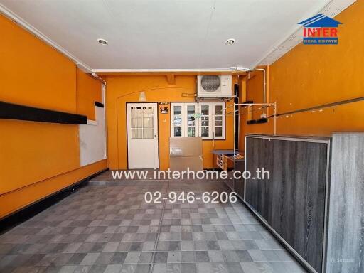 Room with orange walls and window, featuring air conditioner and tiled floor