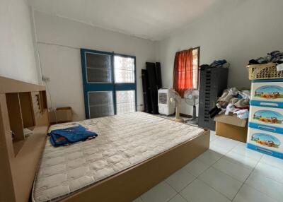 Unfinished bedroom with mattress, fans, and storage