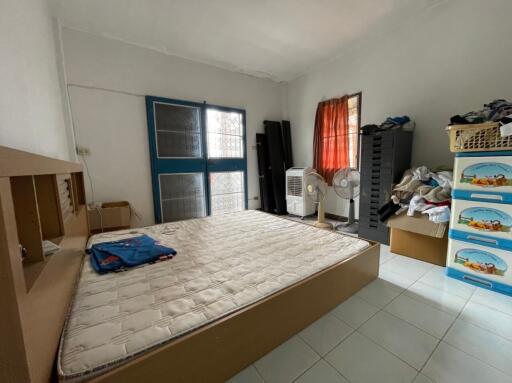 Unfinished bedroom with mattress, fans, and storage