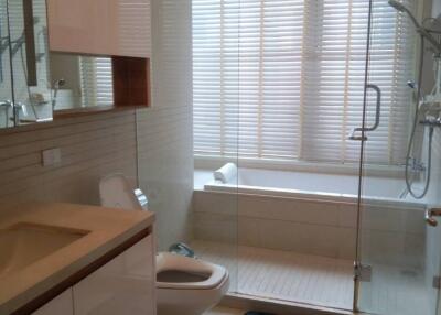 Bathroom with glass-enclosed shower, bathtub, sink, and toilet