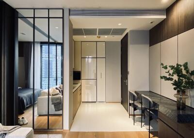 Modern apartment interior including a view of the kitchen, a bedroom, and a dining area