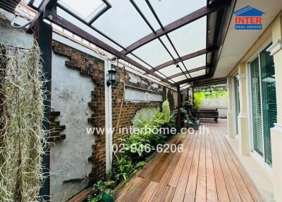 Covered patio area with wooden decking and plants