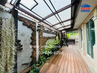 Covered patio area with wooden decking and plants