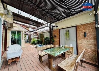 Outdoor patio with wooden flooring, seating area, and plants