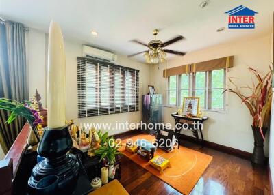 A well-lit living room with hardwood floors, decorated with houseplants and spiritual items.