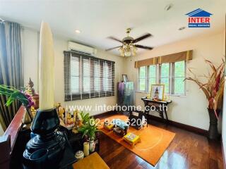 A well-lit living room with hardwood floors, decorated with houseplants and spiritual items.