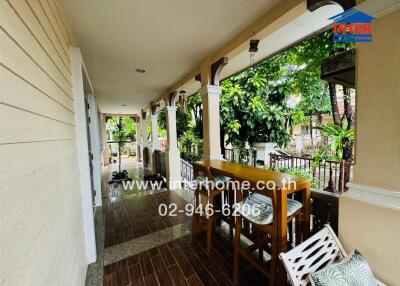 Covered balcony area with seating and view of garden