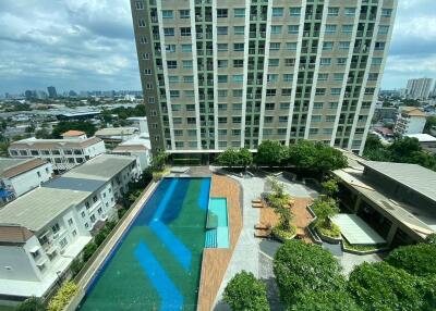 Outdoor swimming pool area viewed from above with adjacent residential building and greenery