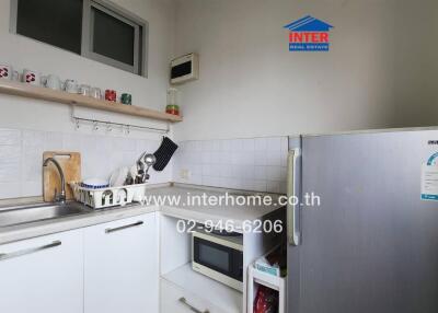 Small kitchen with white cabinets, stainless steel sink, microwave, and refrigerator