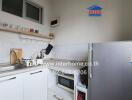 Small kitchen with white cabinets, stainless steel sink, microwave, and refrigerator