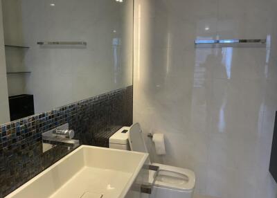 Modern bathroom with white ceramic fixtures and mosaic tile accents