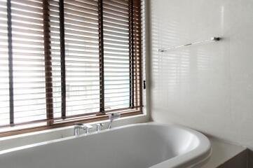 Modern bathroom with bathtub and wooden blinds