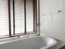 Modern bathroom with bathtub and wooden blinds