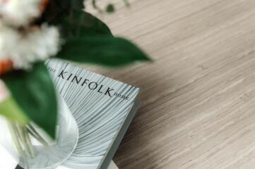 Close-up of a book on a wooden surface with a vase and flowers