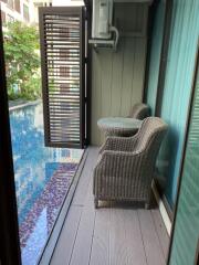 Balcony with wicker chairs and a small table overlooking a swimming pool