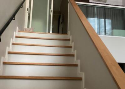 Stairway in a modern home with wooden steps and a glass sliding door at the top