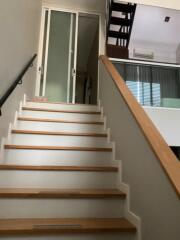 Stairway in a modern home with wooden steps and a glass sliding door at the top