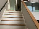 Stairway in a modern home with wooden steps and a glass sliding door at the top