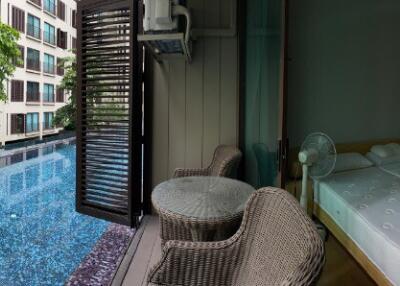 A bedroom with a view of a swimming pool and outdoor seating area