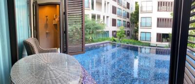 Balcony with outdoor seating overlooking a pool and apartment complex