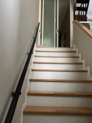 Staircase with wooden steps and glass doors at the top