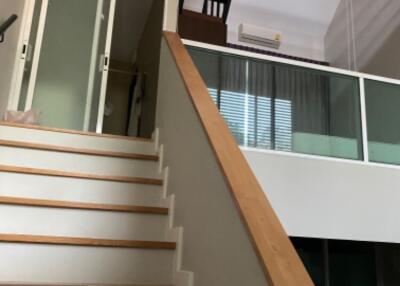 staircase leading to mezzanine with glass railing and air conditioning unit