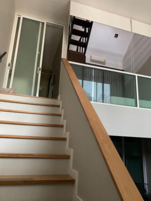 staircase leading to mezzanine with glass railing and air conditioning unit