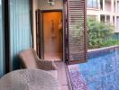 A serene poolside view with outdoor seating and apartment buildings in the background