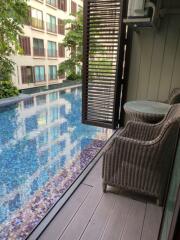 Balcony with wicker chairs and table overlooking a swimming pool