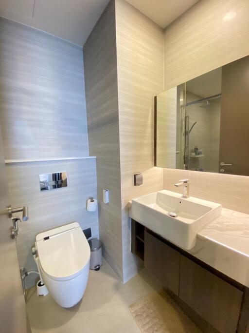 Modern bathroom with a large mirror, sink, and toilet