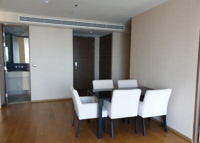 Modern dining area with wooden flooring and four white upholstered chairs around a black dining table.