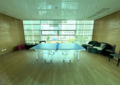 Spacious recreation room with table tennis setup, city view through large windows.