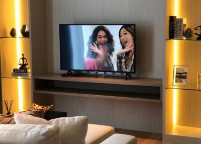 Modern living room with a wall-mounted TV and illuminated shelves