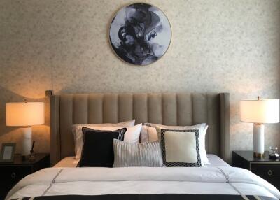 A well-decorated bedroom with a neatly made bed, decorative pillows, and bedside lamps.