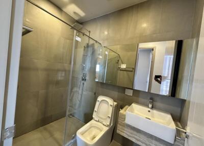 Modern bathroom with glass shower, toilet, and sink