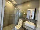 Modern bathroom with glass shower, toilet, and sink