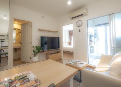 Living room with TV, modern decor, and view into bedroom and bathroom