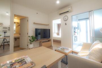 Living room with TV, modern decor, and view into bedroom and bathroom