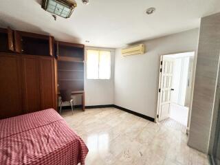 Spacious bedroom with bed, cabinets, desk, and window