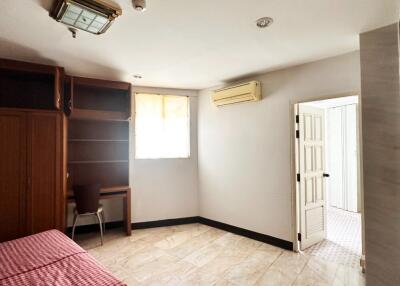 Spacious bedroom with window, air conditioning, built-in shelves, and an adjacent bathroom