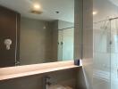 Modern bathroom with large mirror, sink, and glass shower