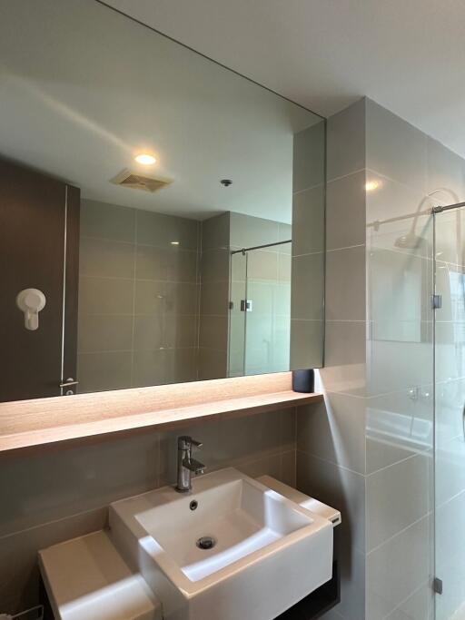 Modern bathroom with large mirror, sink, and glass shower