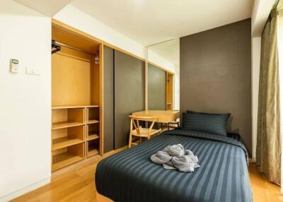 Modern bedroom with wooden floor, open closet, single bed, and study desk by the window