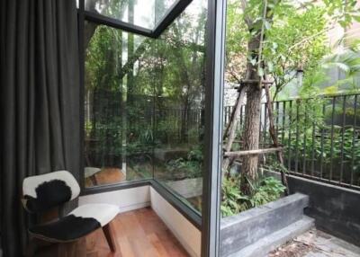 Small balcony with large glass windows overlooking a lush garden